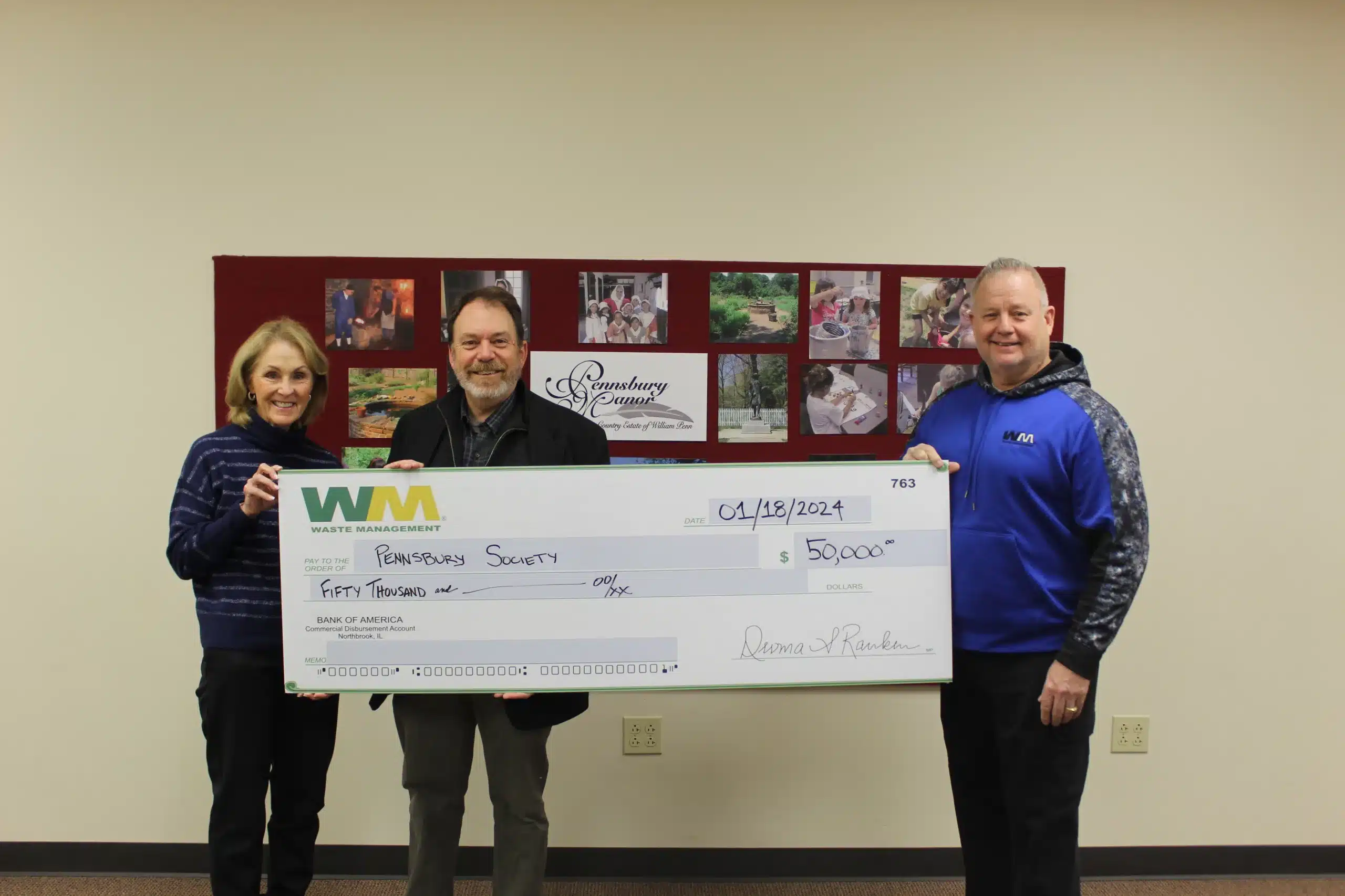 Check presentation photo. Three people are holding a large check for $50,000 from Waste Management