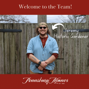 Jeremy the new gardener smiling in front of a garden fence.